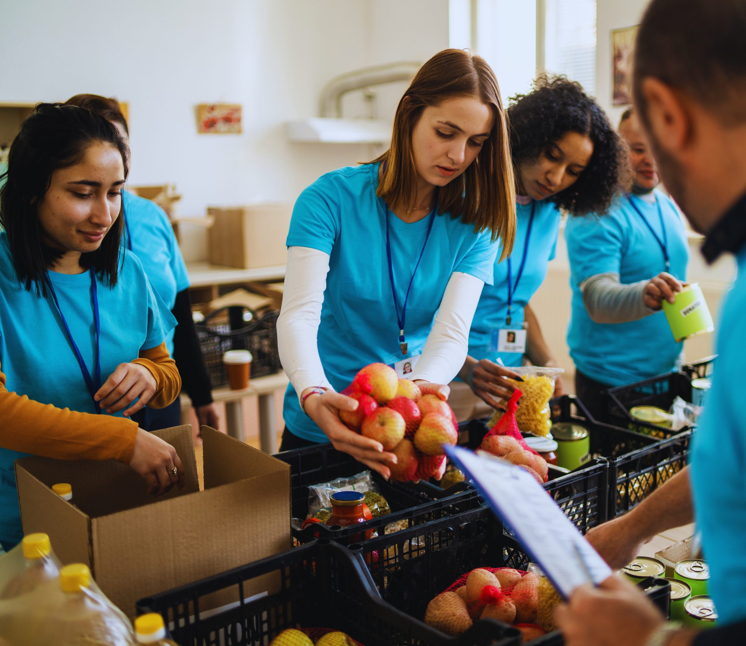 FoodSecurity_CauseArea_Header People wearing blue pack food containers at a food bank.