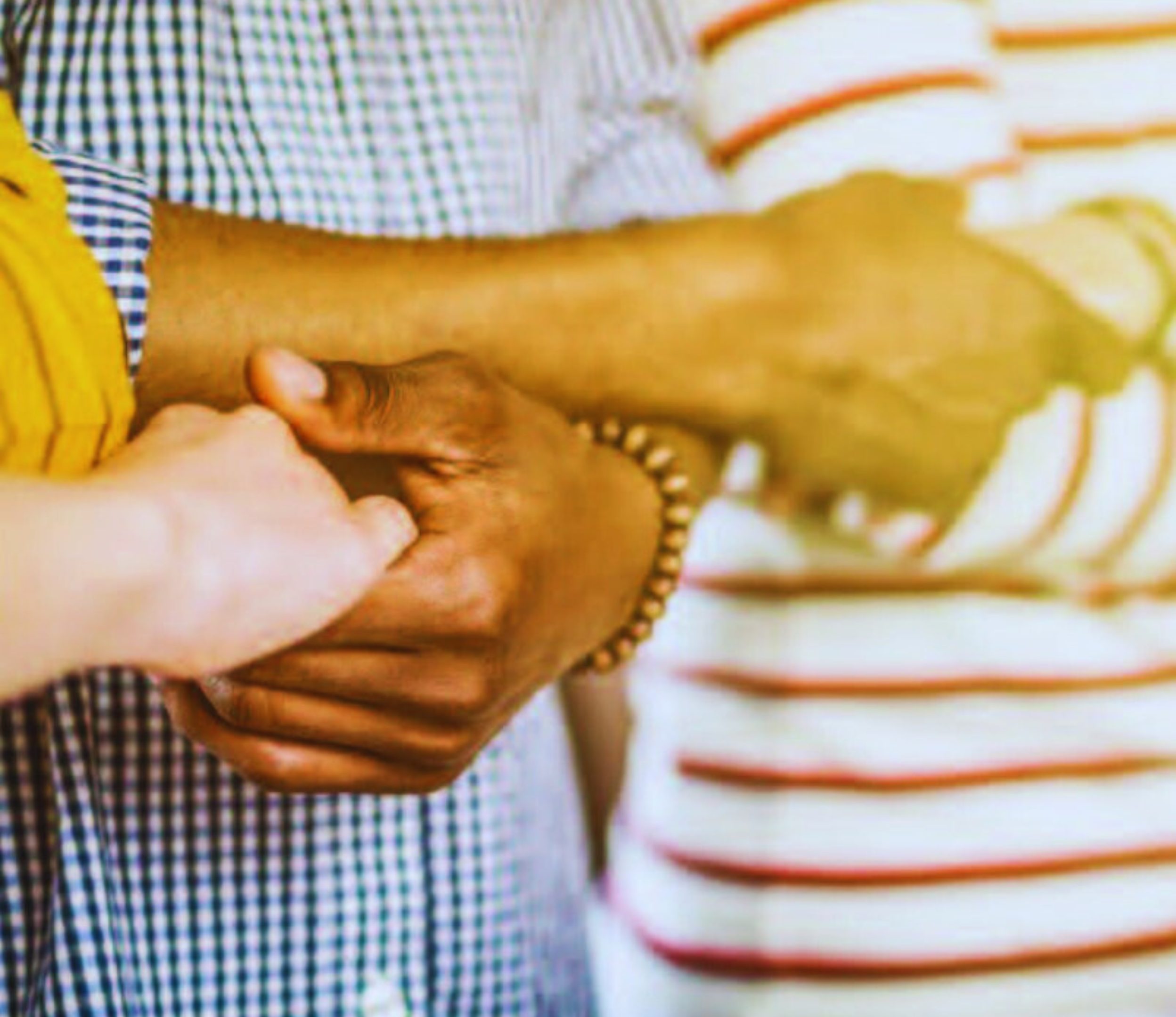People holding hands who are wearing a gingham shirt and a striped shirt