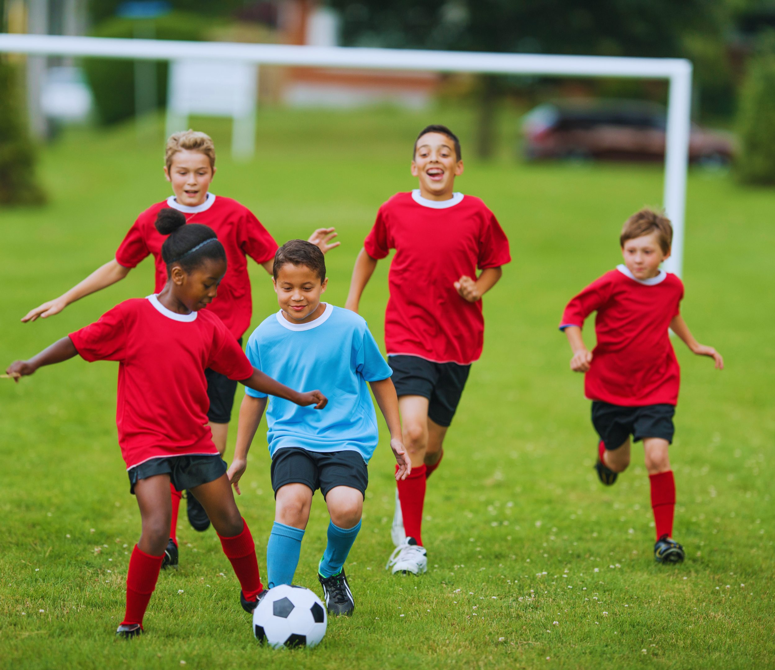 KidsSoccer_SportsCause_Header Kids playing soccer in a field.