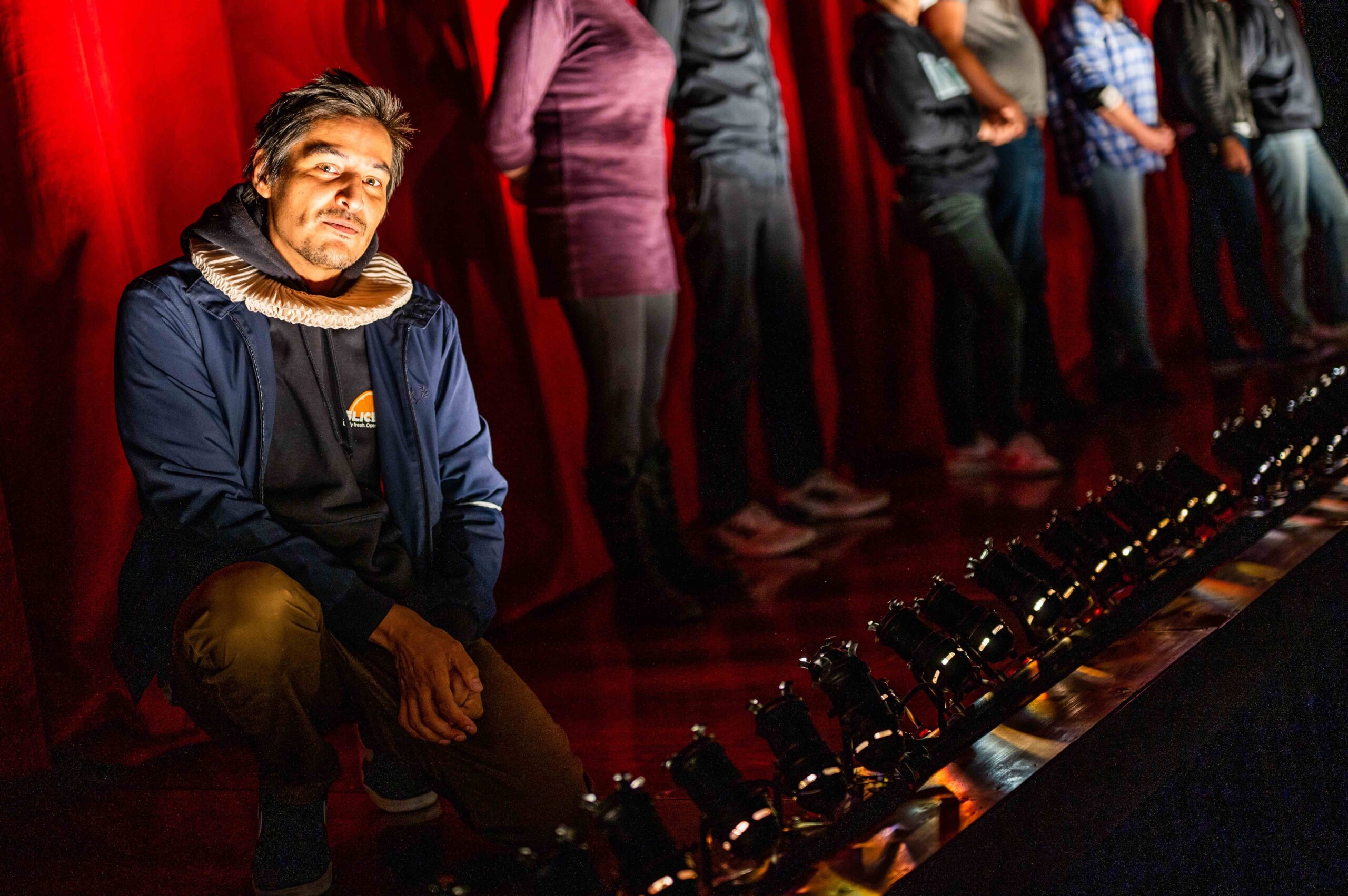 A performer kneels onstage and smiles at the camera, during a performance at Artspring.