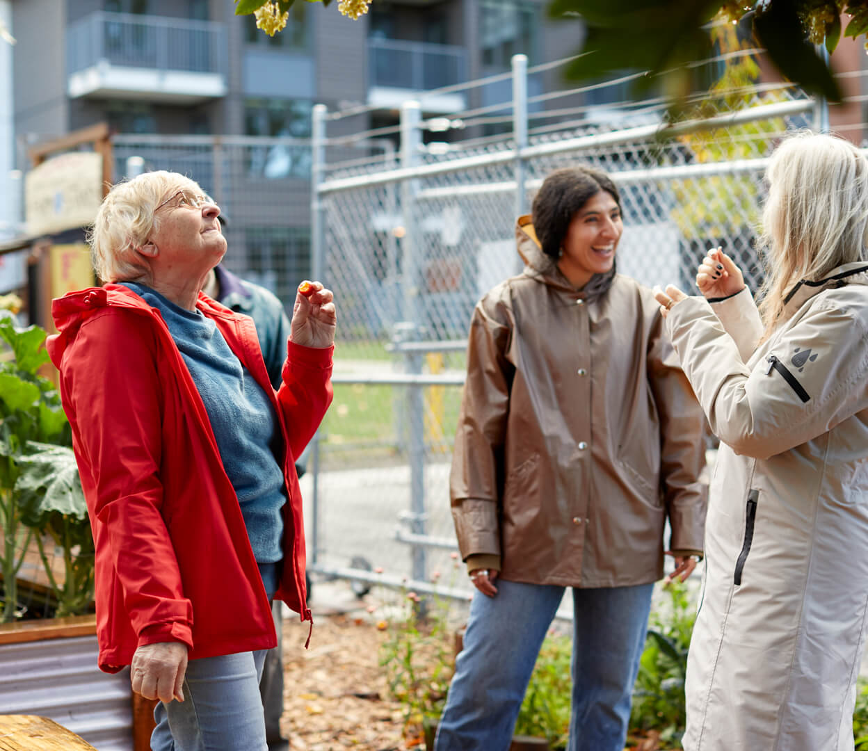 An educator from the Compost Education Centre explains the fruit of the strawberry tree to two women.