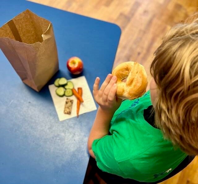 Child eating lunch packed in brown bag.