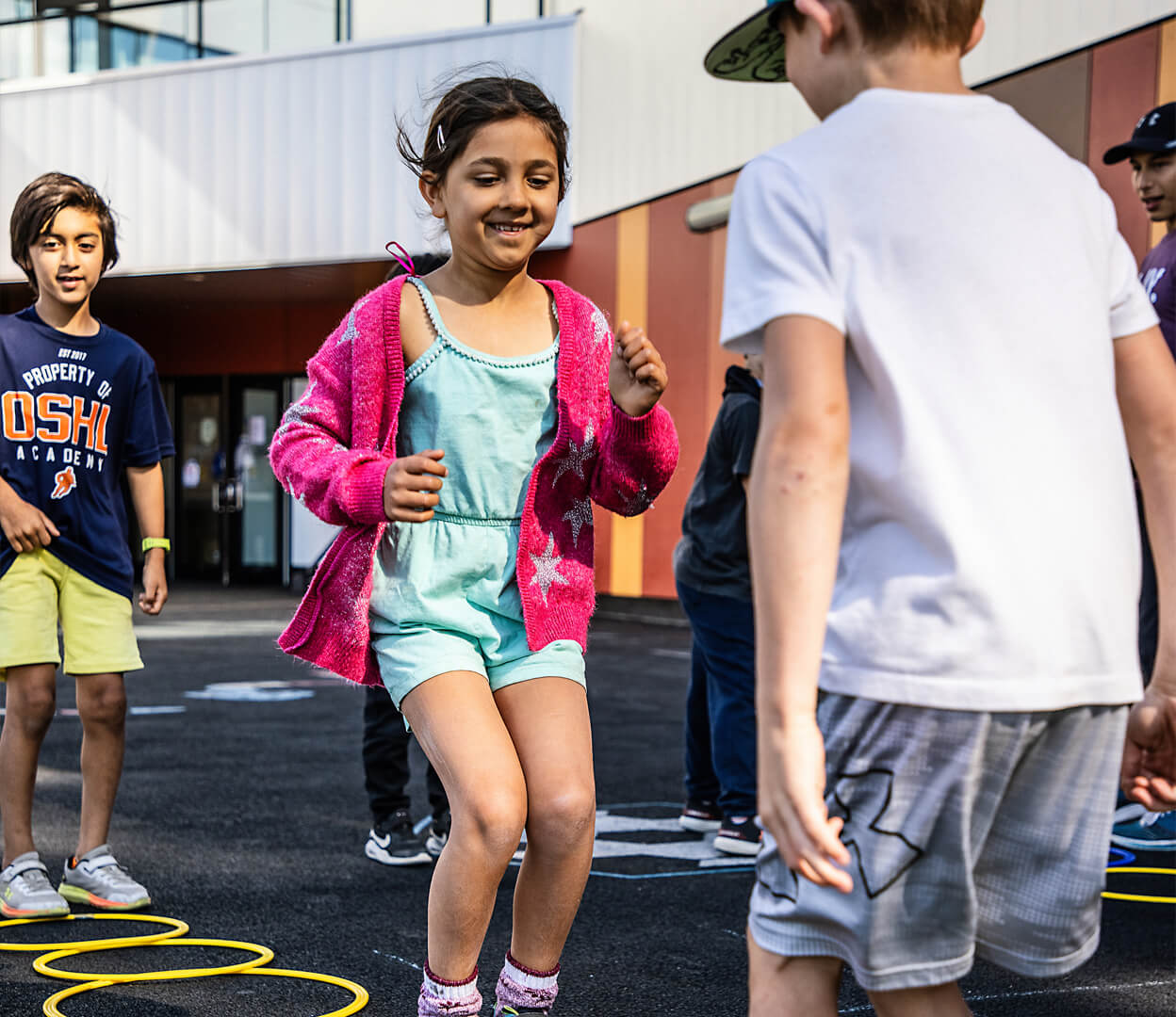 Young children play a game with hula hoops at the Pacific Institute for Sport Education.