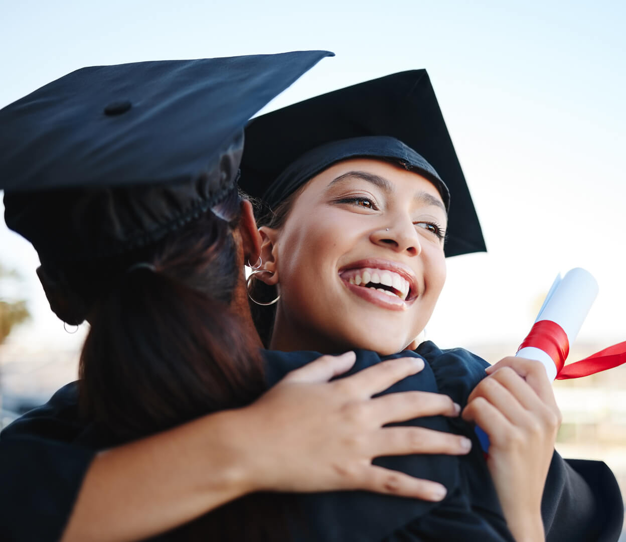 A student hugs another student at a university graduation ceremony.