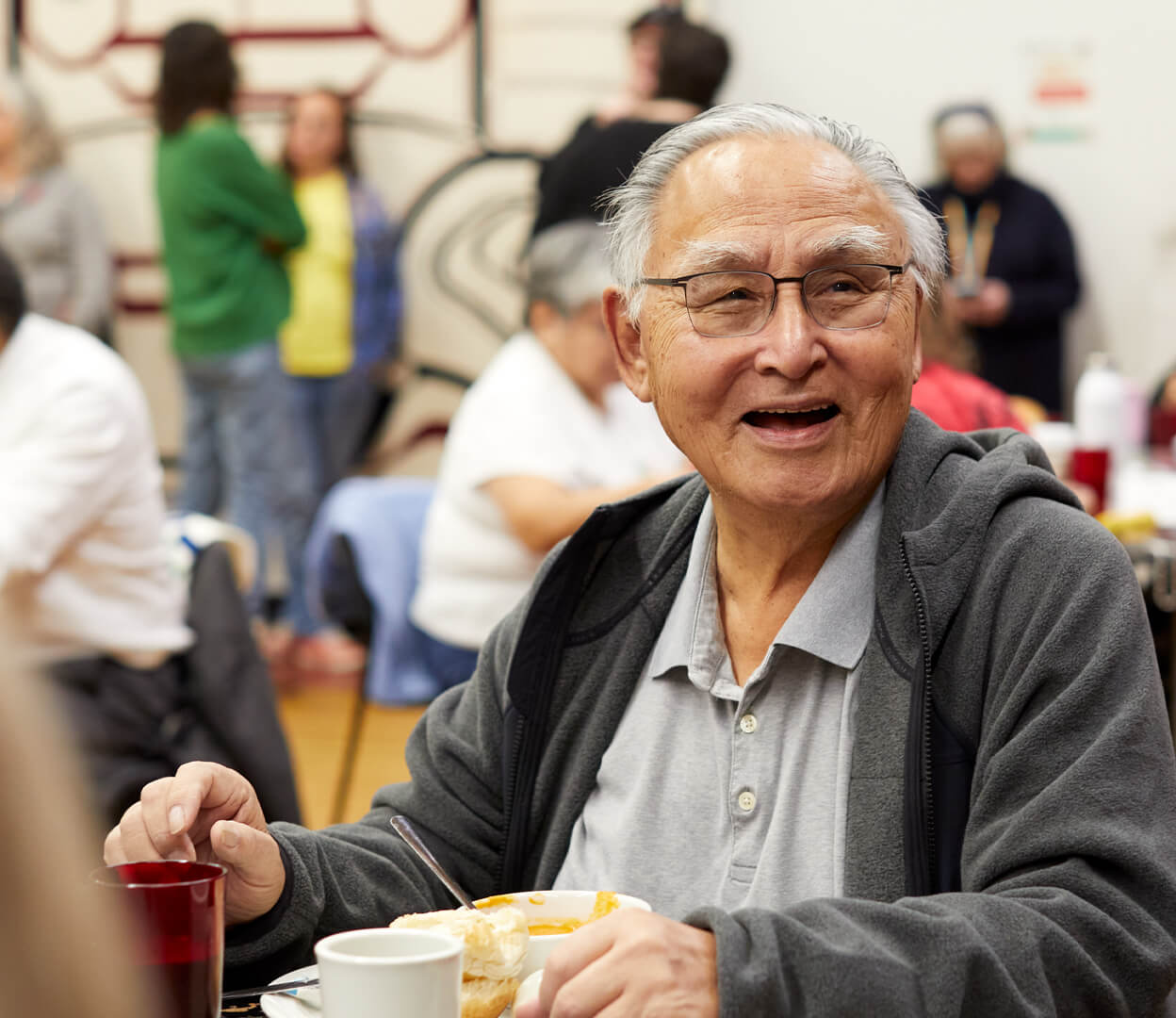 An elderly man laughs while enjoying lunch at the Victoria Native Friendship Centre.