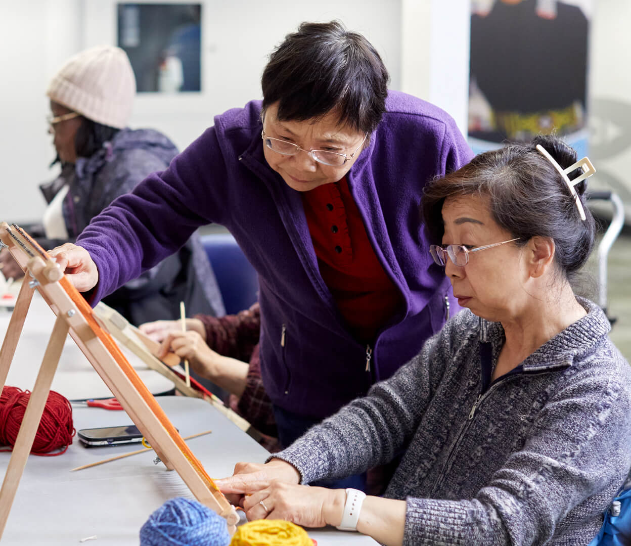An instructor helps a woman with a weaving loom in a workshop put on by the Inter-cultural Association of Greater Victoria.