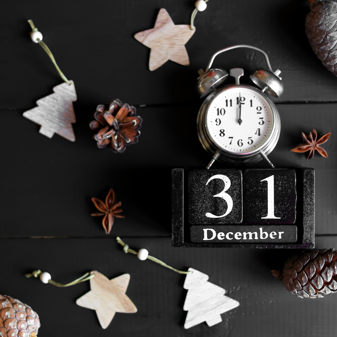 An alarm clock sitting on top of a calendar showing December 31.