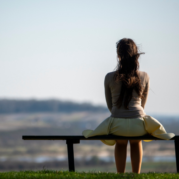 A woman sits on a bench overlooking the city.