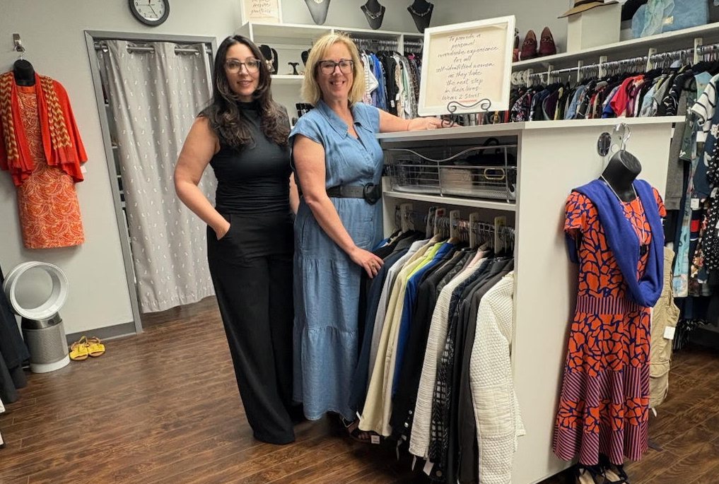 Wear 2 Start board members stand among the clothing racks at the charity's location.