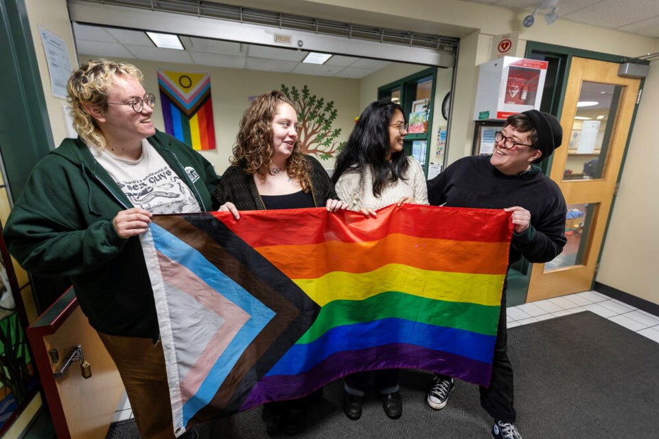 Employees at the Oaklands Community Centre hold up a pride flag together.