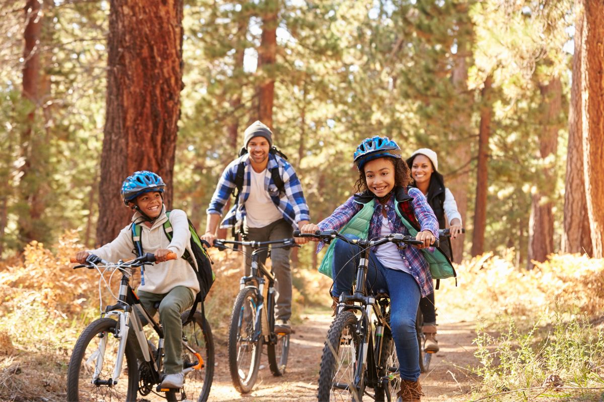 A family bikes happily through the forest.