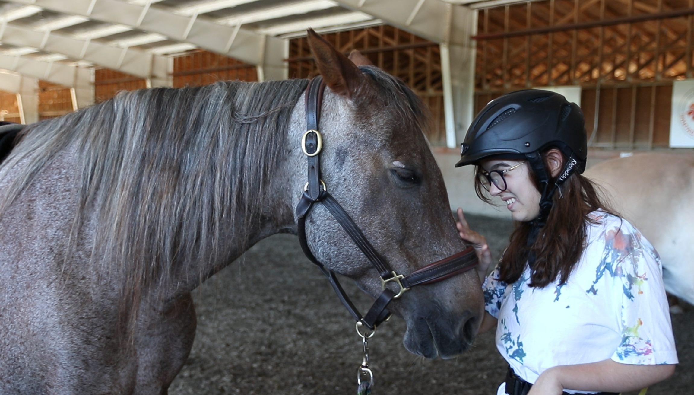 Victoria Therapeutic Riding Association client enjoys petting her horse.