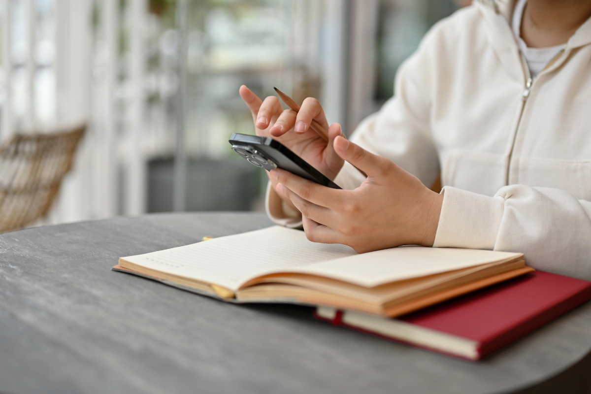 A person sits at a table, using Epilogue to create their Will on their smartphone.
