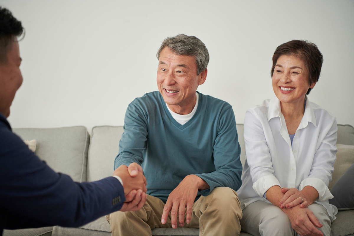 A couple sit on a sofa across from a professional advisor.