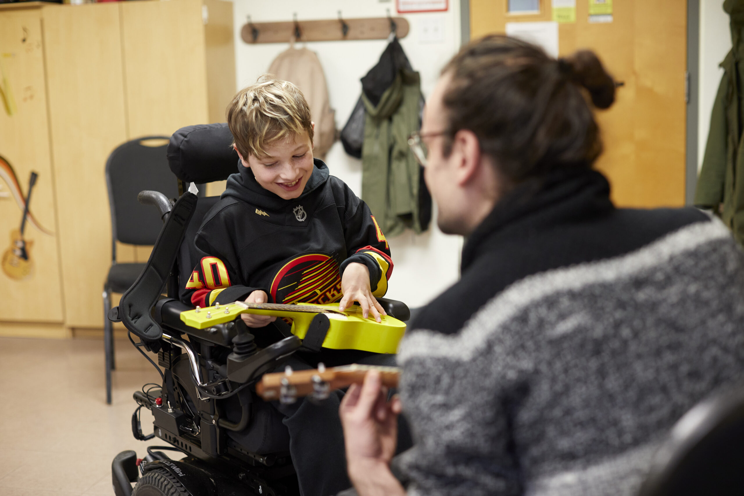 A little boy in a wheelchair learns to play the ukulele, at the Victoria Conservatory of Music.