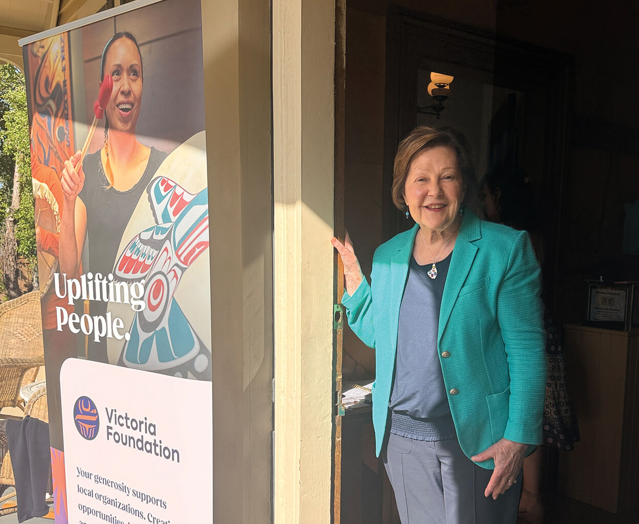 Sandra Richardson in a doorway beside a Victoria Foundation poster